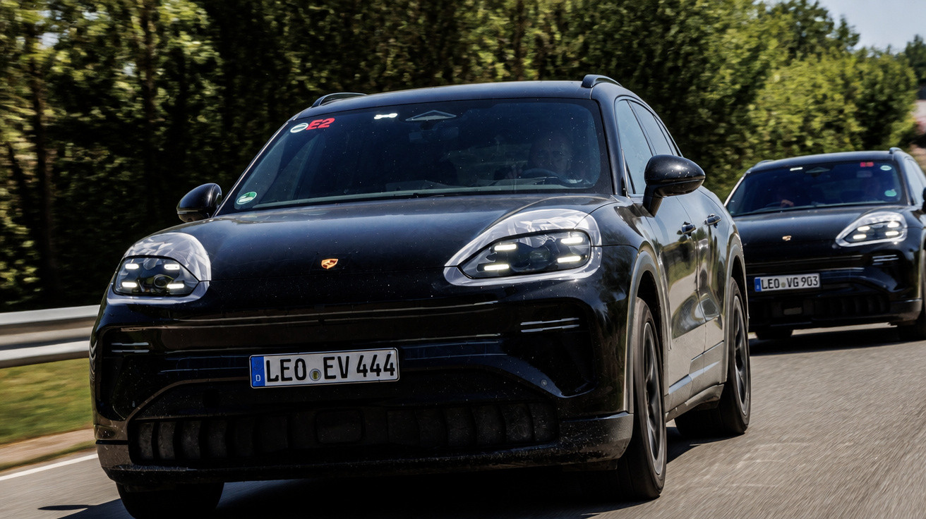 Dois carros elétricos Porsche Taycan preto em estrada cercada por árvores.