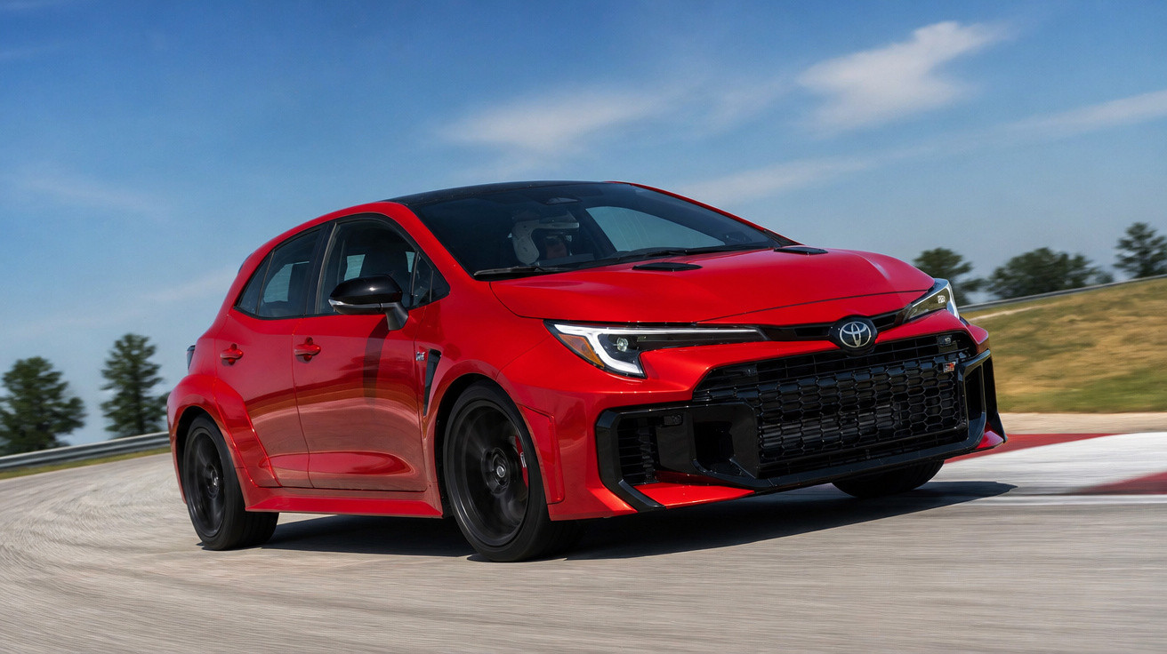 Carro esportivo hatchback vermelho em alta velocidade em uma pista de corrida curva.