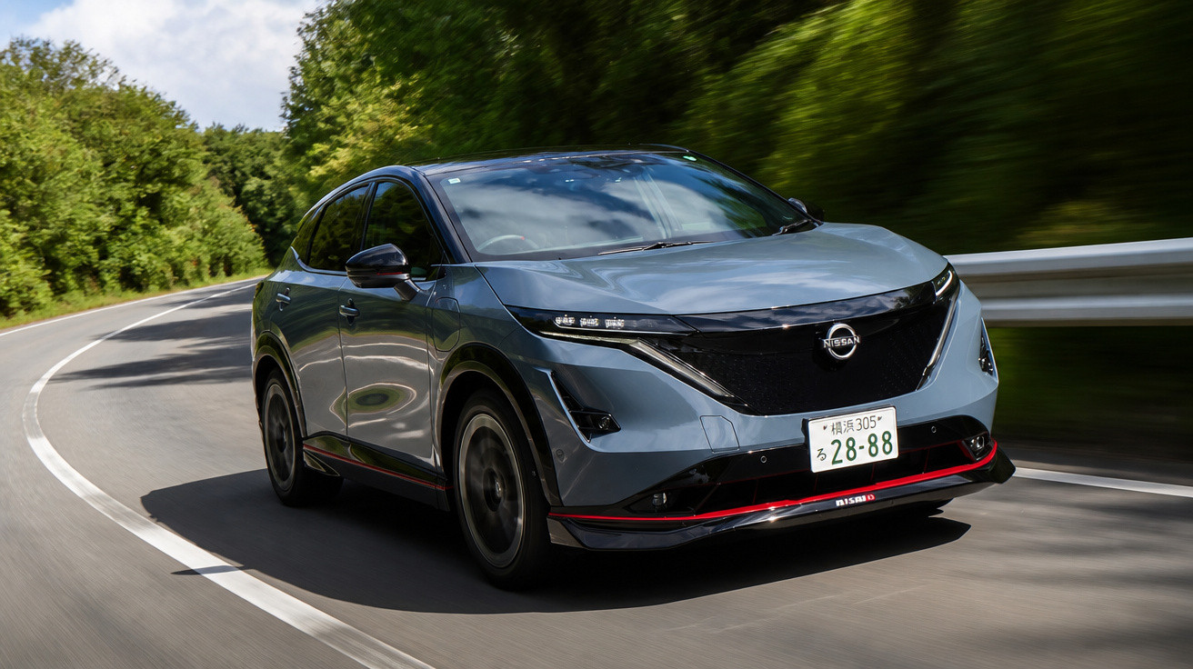 Carro elétrico Nissan Ariya cinza em uma estrada sinuosa cercada por árvores verdes.