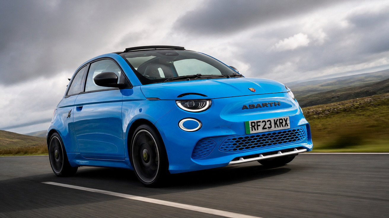 Carro esportivo azul Abarth em movimento na estrada com céu nublado ao fundo.
